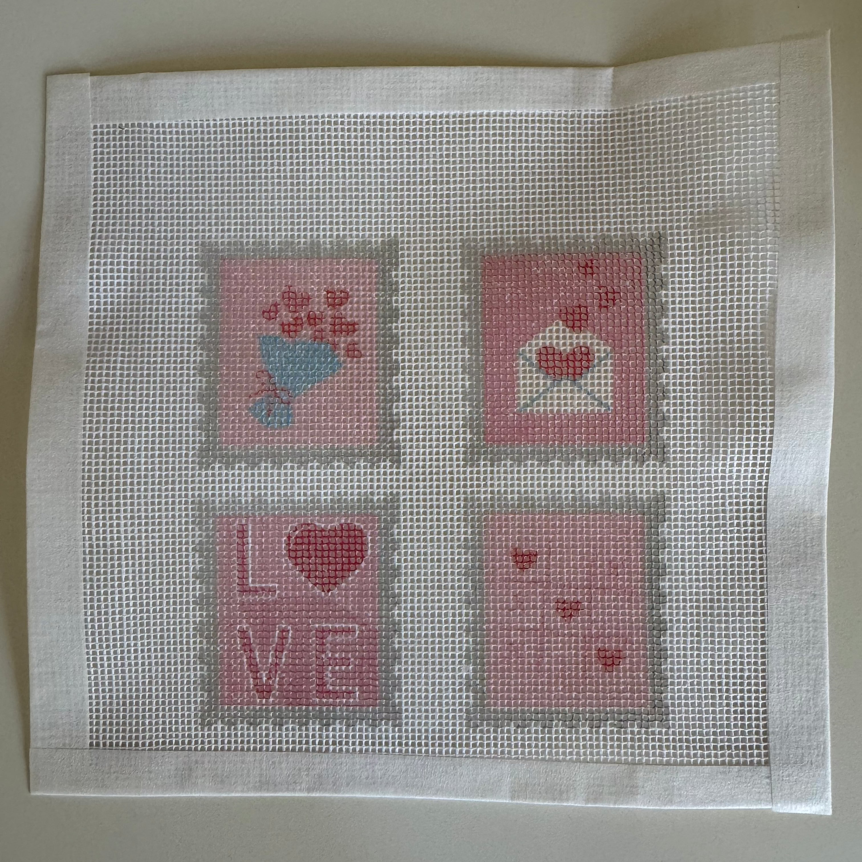 Cross-stitched design on fabric with heart and 'LOVE' pattern